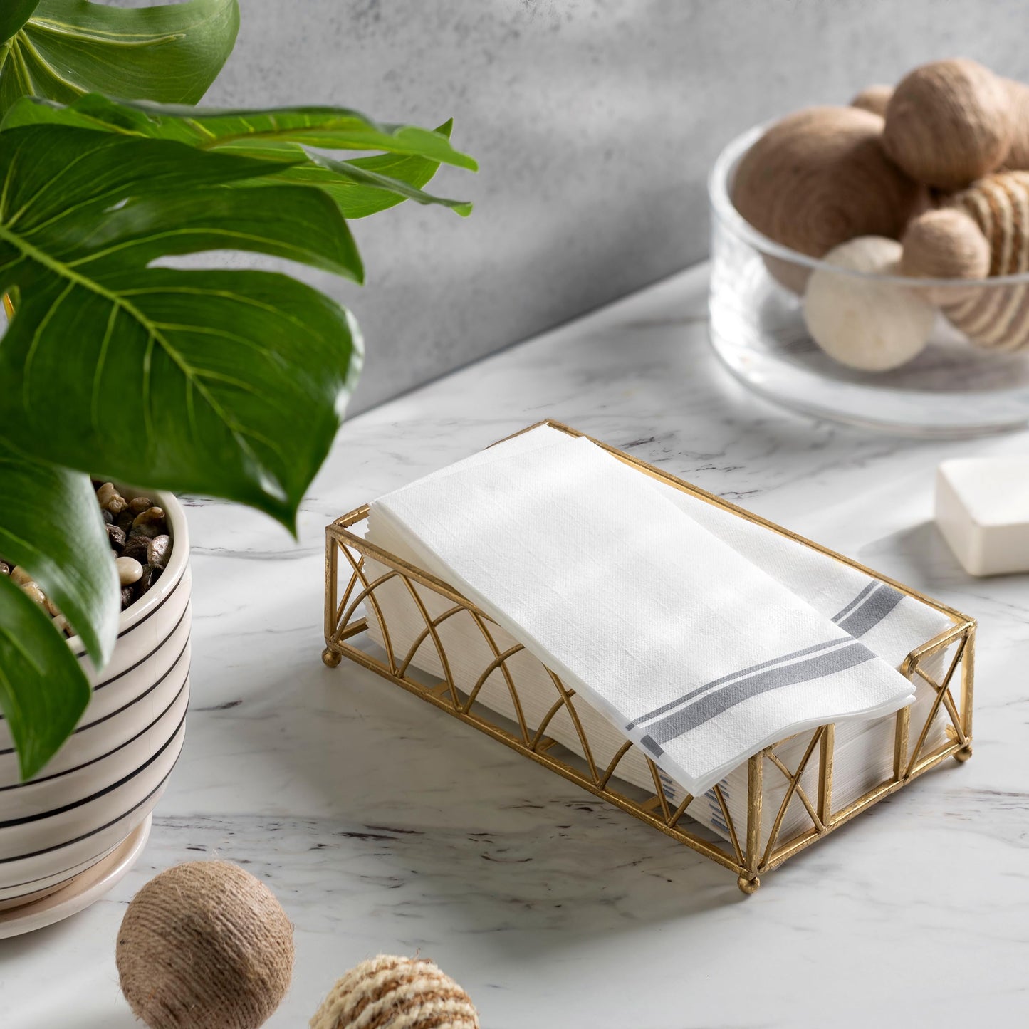 Disposable silver double-line napkins displayed in tray atop table