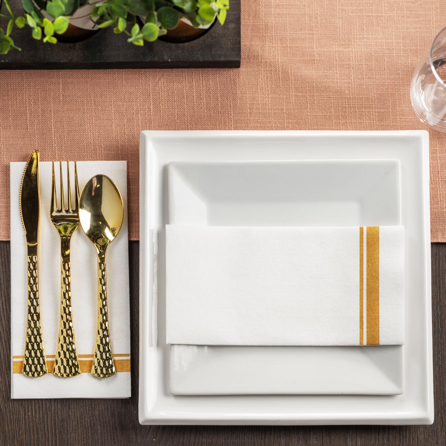Linen-feel disposable guest towel with elegant double-line gold foil border at formal table gathering