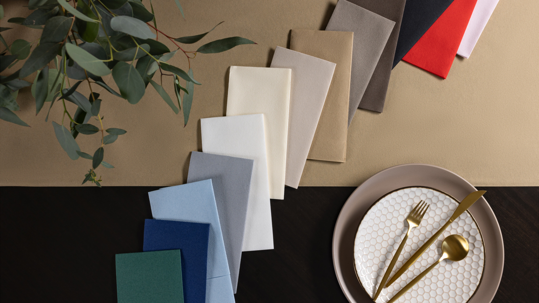 Airland dinner napkins in multiple colors are fanned out across a black and gold table.