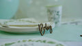 A close-up image shows baby shower napkins cups and plates. A wooden sign that says Baby is propped up against the plates.