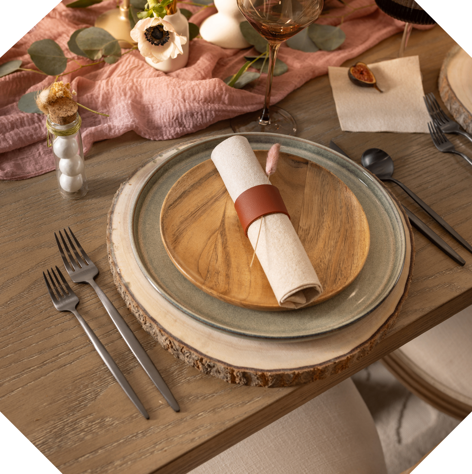 Dining table setting with plates, cutlery, and decorative elements on a wooden surface.