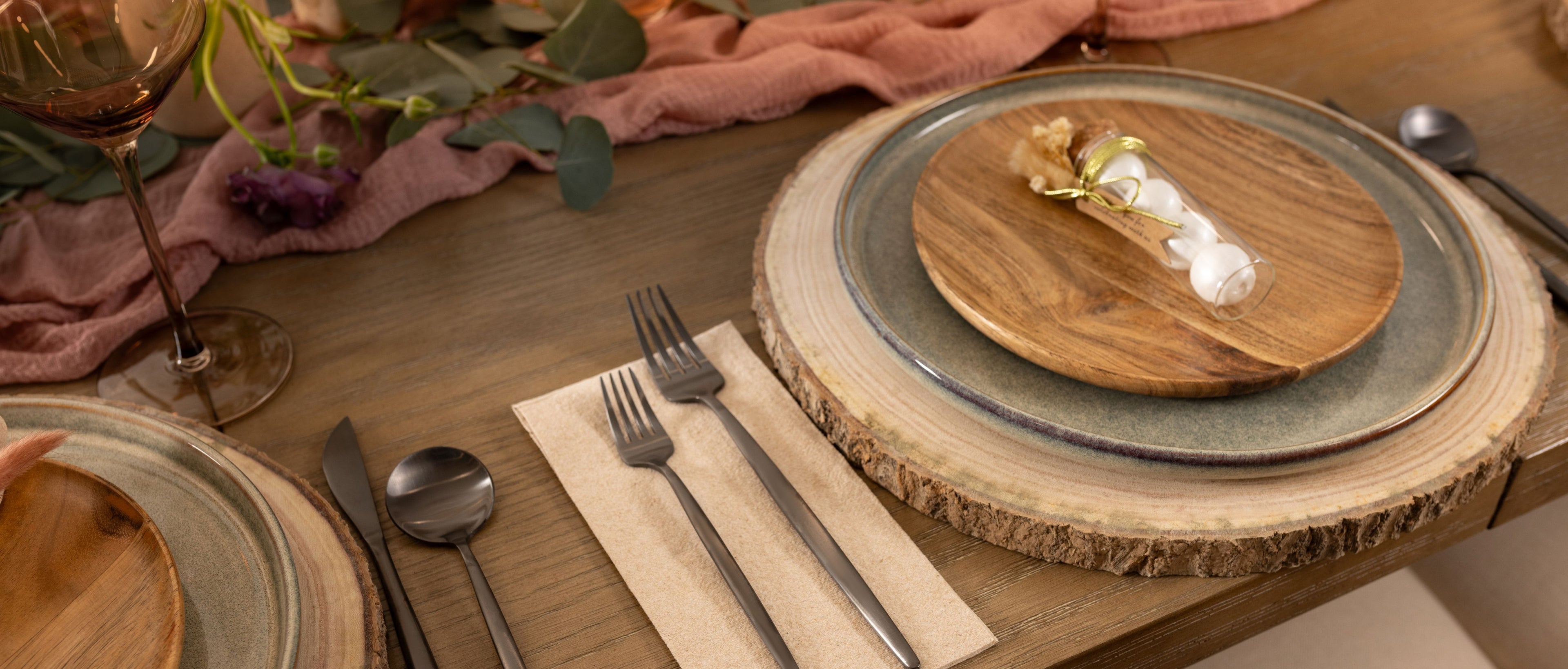 Dining table setup with plates, cutlery, and a decorative wooden board.